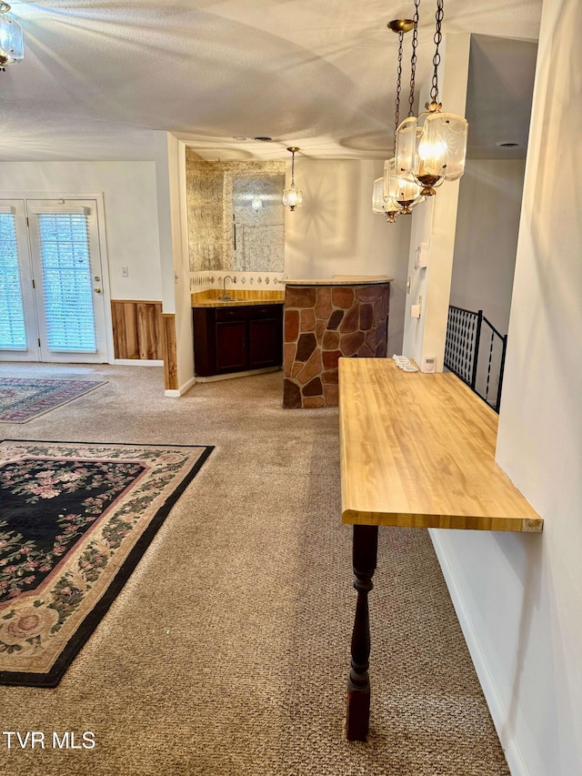 dining space with sink, carpet, and a textured ceiling