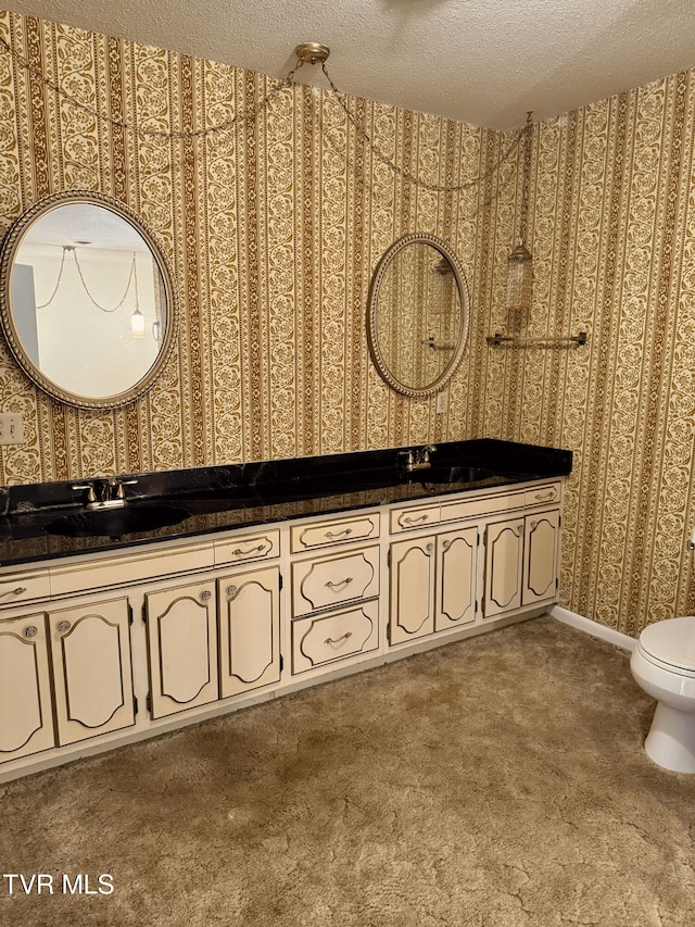 bathroom with vanity, toilet, and a textured ceiling