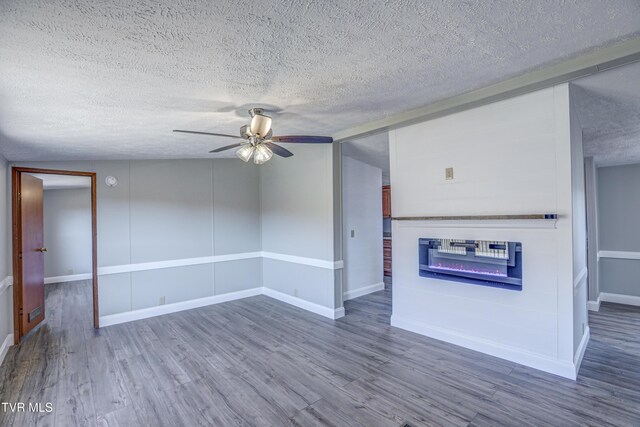 252 Scott Ln, Blountville, TN 37617 - unfurnished living room featuring a textured ceiling, baseboards, ceiling fan, wood finished floors, and a glass covered fireplace