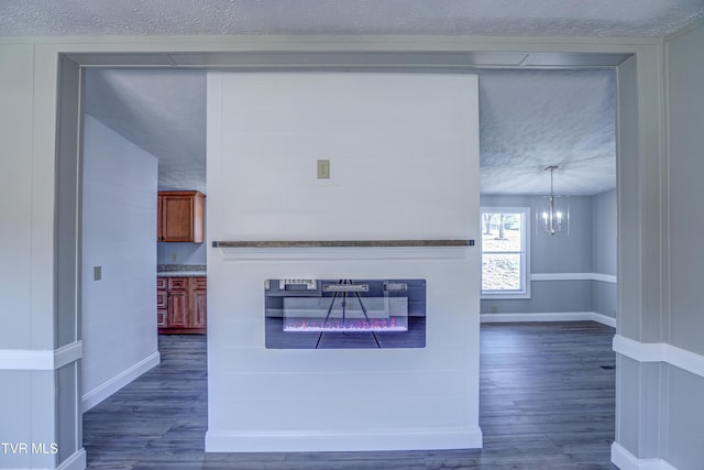 252 Scott Ln, Blountville, TN 37617 - interior space featuring an inviting chandelier, baseboards, a textured ceiling, dark wood finished floors, and a glass covered fireplace