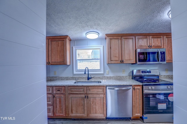 252 Scott Ln, Blountville, TN 37617 - kitchen with a textured ceiling, a sink, brown cabinets, and appliances with stainless steel finishes