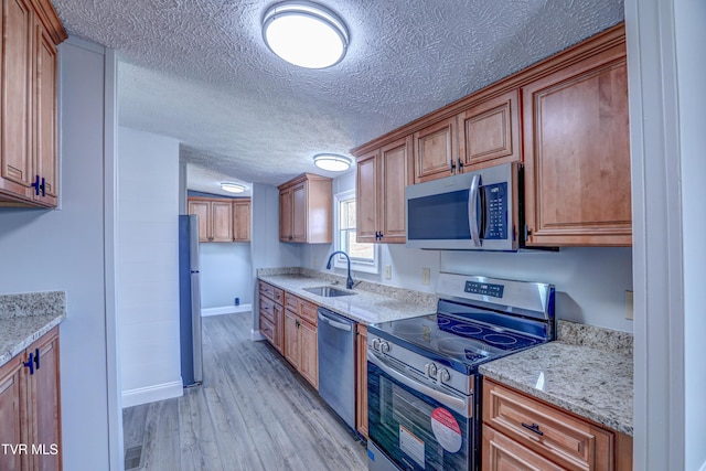 252 Scott Ln, Blountville, TN 37617 - kitchen with light stone counters, a sink, light wood finished floors, appliances with stainless steel finishes, and a textured ceiling