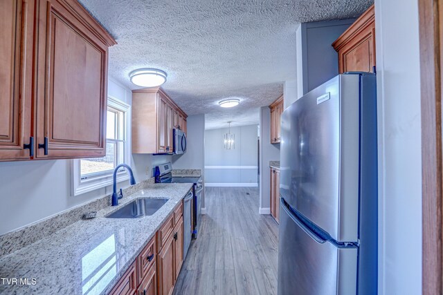 252 Scott Ln, Blountville, TN 37617 - kitchen featuring a textured ceiling, light stone countertops, appliances with stainless steel finishes, a sink, and light wood-style floors