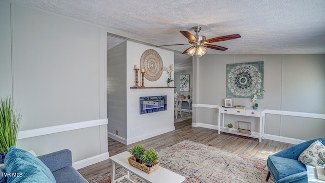 252 Scott Ln, Blountville, TN 37617 - living room featuring a ceiling fan, a glass covered fireplace, a textured ceiling, and wood finished floors