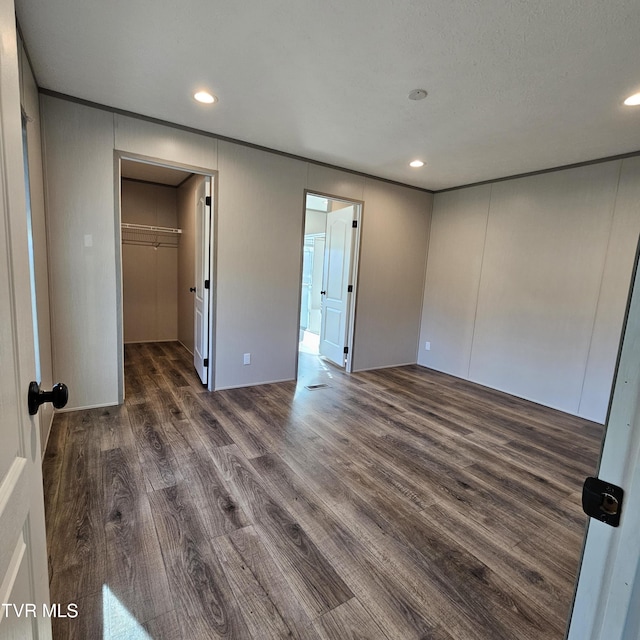 unfurnished bedroom featuring dark hardwood / wood-style flooring, a walk in closet, and a closet