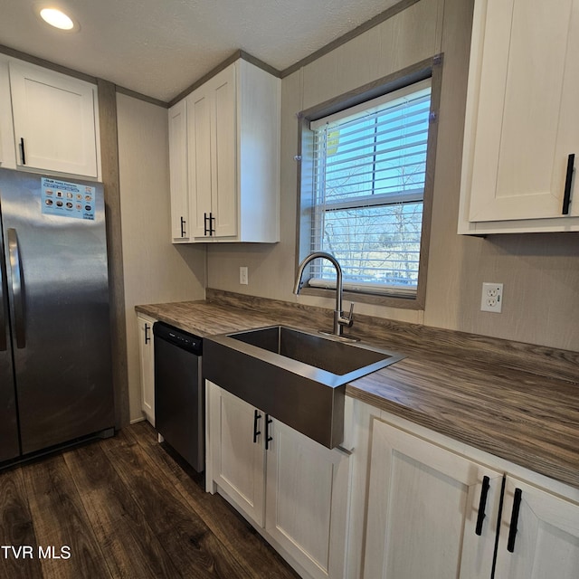 kitchen with butcher block countertops, sink, dark hardwood / wood-style floors, stainless steel appliances, and white cabinets