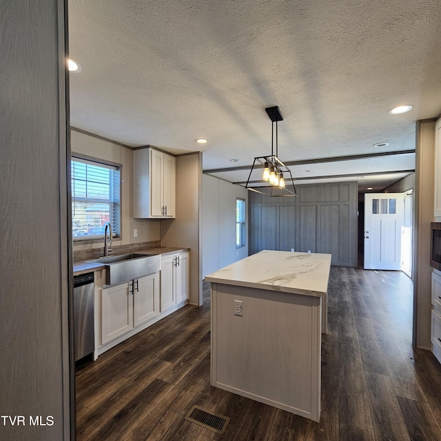 kitchen with white cabinetry, sink, hanging light fixtures, stainless steel dishwasher, and a textured ceiling