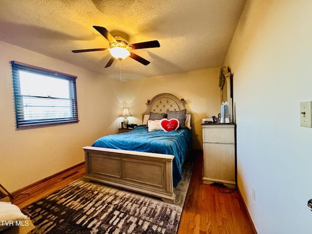 bedroom with a textured ceiling, dark hardwood / wood-style floors, and ceiling fan