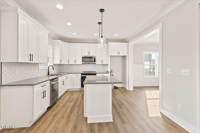 kitchen with white cabinetry, stainless steel appliances, a center island, and dark stone countertops