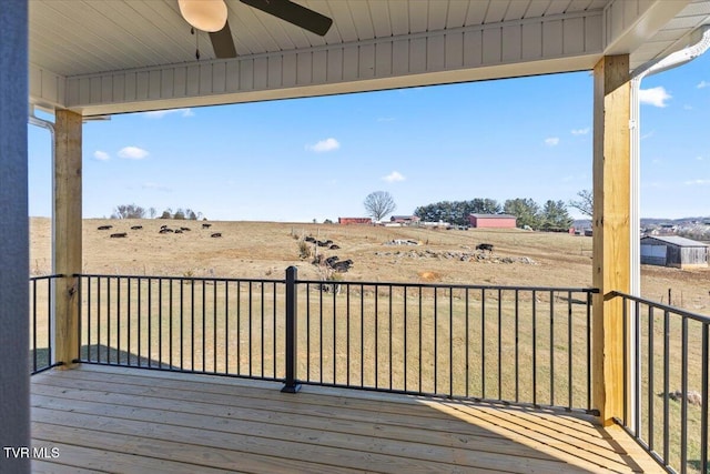 deck with ceiling fan, a yard, and a rural view