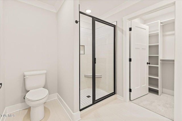 bathroom featuring a shower with shower door, ornamental molding, and toilet