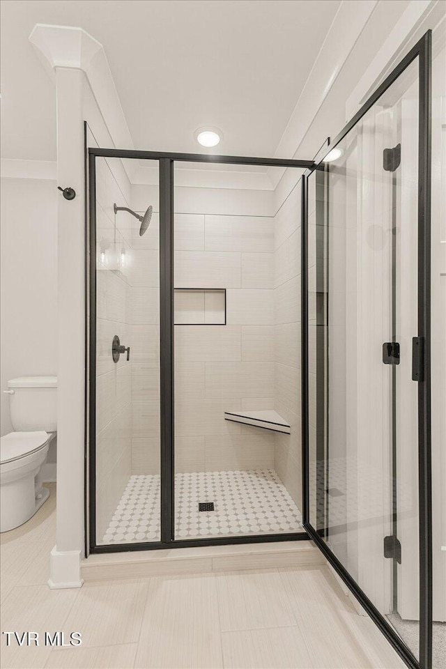 bathroom featuring toilet, an enclosed shower, and tile patterned flooring