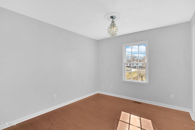 unfurnished room featuring wood-type flooring and a chandelier