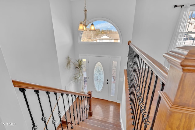 entryway with a notable chandelier, a towering ceiling, hardwood / wood-style floors, and a healthy amount of sunlight