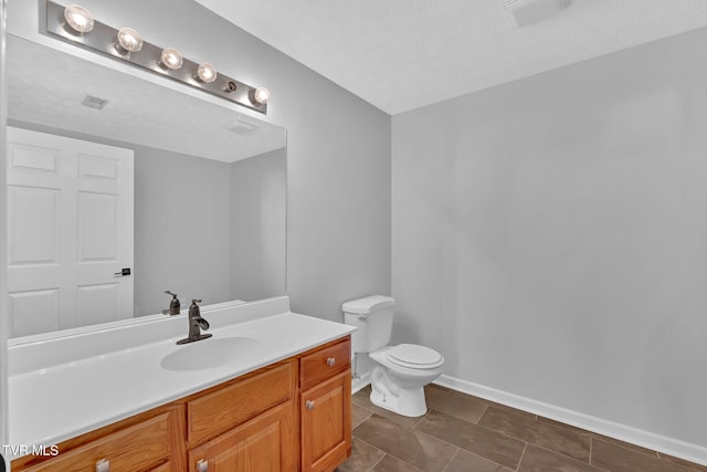 bathroom with vanity, toilet, and a textured ceiling