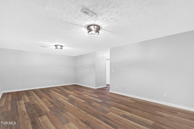 empty room with dark hardwood / wood-style floors and a textured ceiling