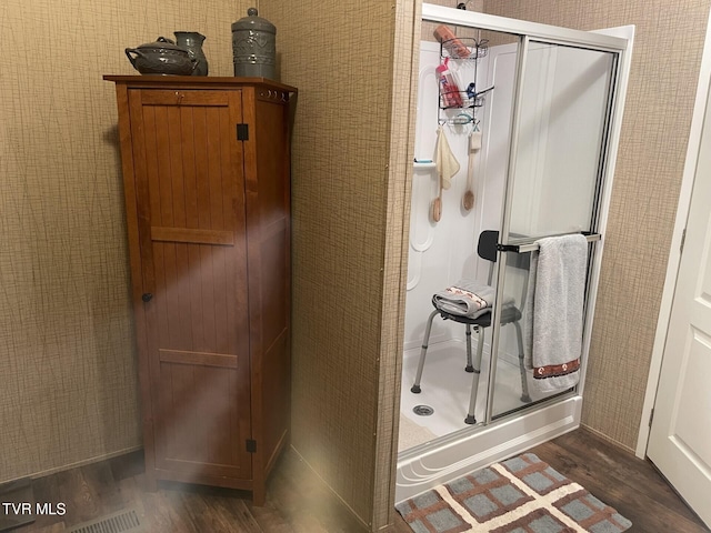 bathroom with hardwood / wood-style floors and a shower with shower door