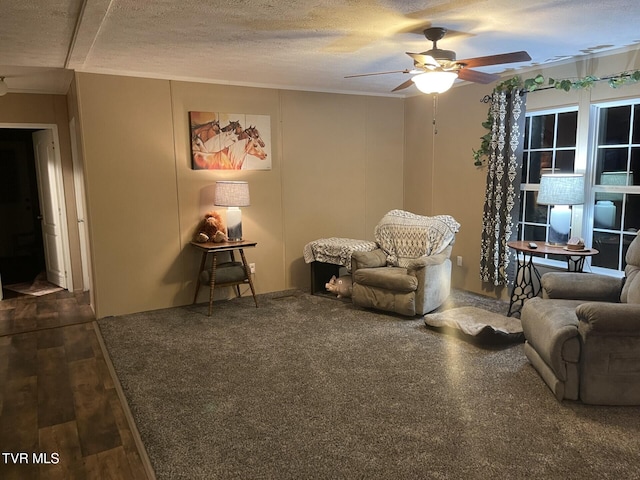 sitting room with ceiling fan, dark wood-type flooring, and a textured ceiling