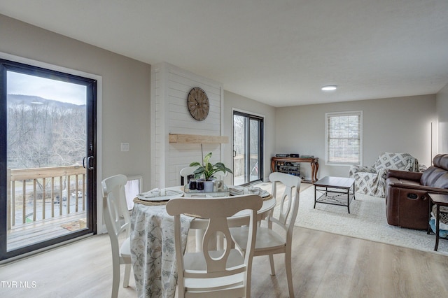 dining room featuring a mountain view, light hardwood / wood-style flooring, and a fireplace