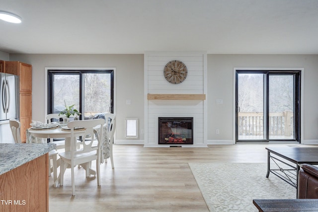 dining space with a large fireplace and light hardwood / wood-style flooring