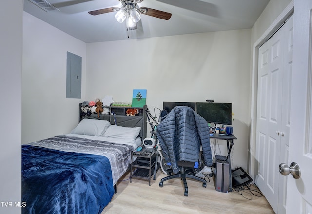 bedroom with ceiling fan, electric panel, light hardwood / wood-style floors, and a closet