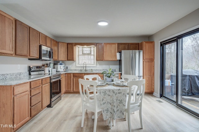 kitchen with stainless steel appliances, sink, and light hardwood / wood-style flooring