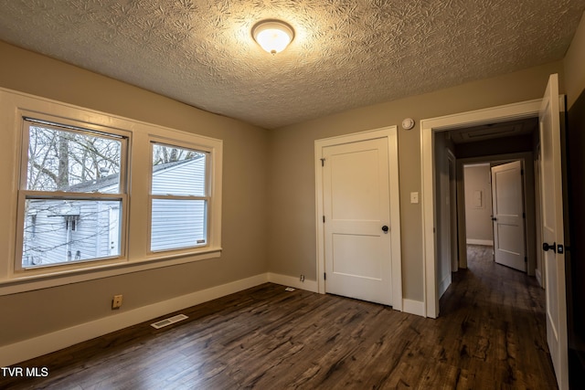 unfurnished bedroom with dark hardwood / wood-style floors and a textured ceiling