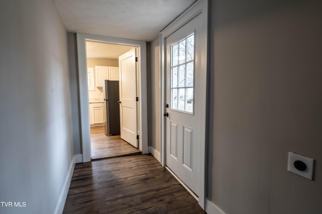 doorway to outside featuring dark wood-type flooring and a textured ceiling