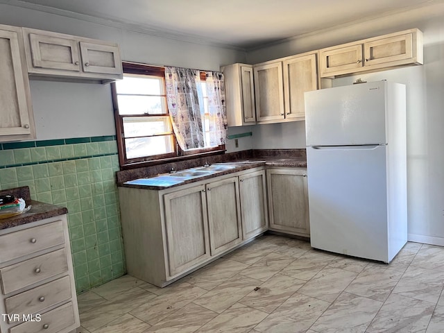 kitchen featuring white refrigerator, crown molding, sink, and tile walls