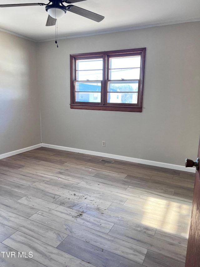 empty room featuring ornamental molding, ceiling fan, and light wood-type flooring