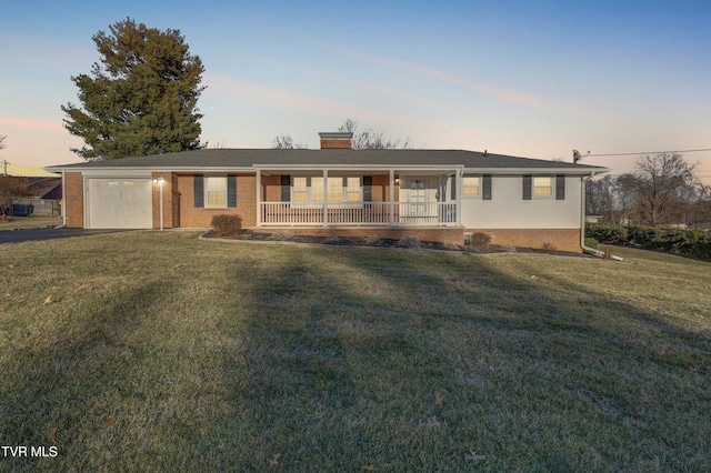 ranch-style home with a garage, a yard, and covered porch