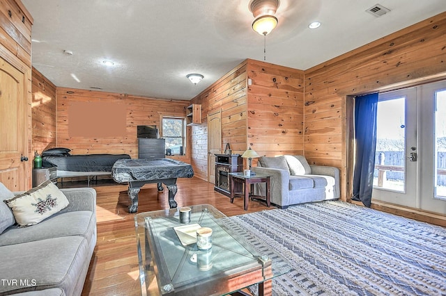 living room with recessed lighting, wood walls, wood finished floors, visible vents, and french doors