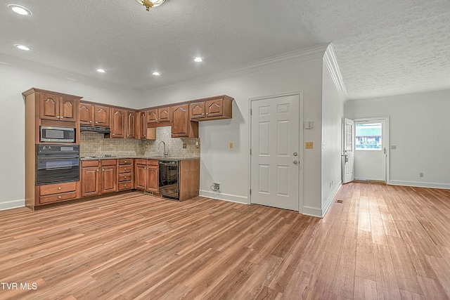 kitchen featuring sink, light wood-type flooring, ornamental molding, appliances with stainless steel finishes, and decorative backsplash