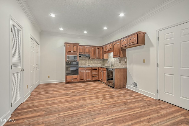 kitchen with crown molding, hardwood / wood-style flooring, appliances with stainless steel finishes, backsplash, and light stone counters