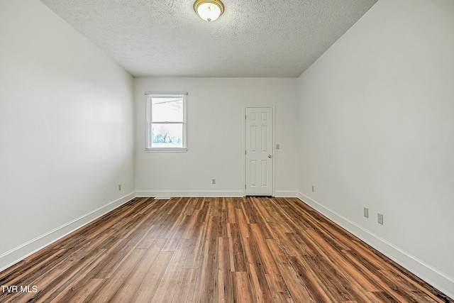 empty room with dark hardwood / wood-style flooring and a textured ceiling