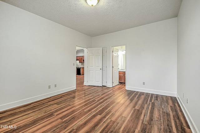 unfurnished bedroom with connected bathroom, a textured ceiling, and dark hardwood / wood-style flooring