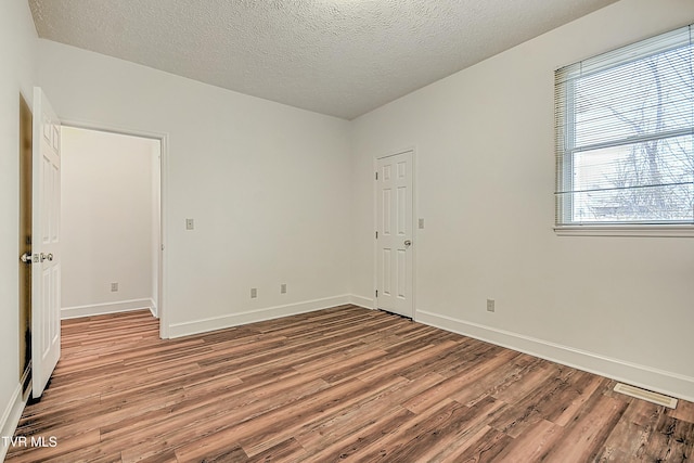 spare room with a textured ceiling and light wood-type flooring