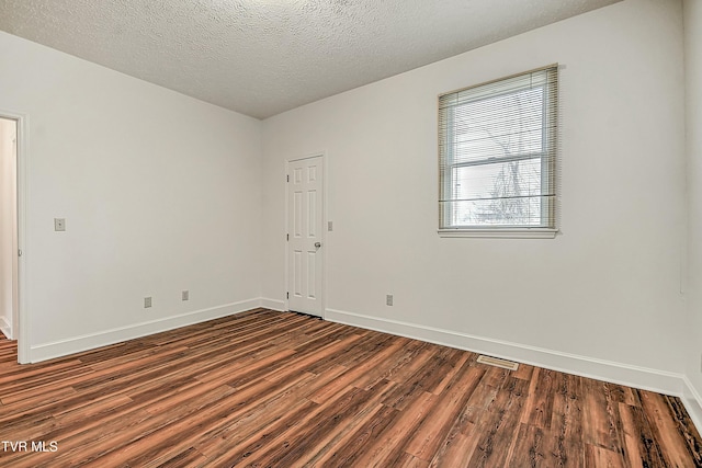 empty room with dark hardwood / wood-style flooring and a textured ceiling