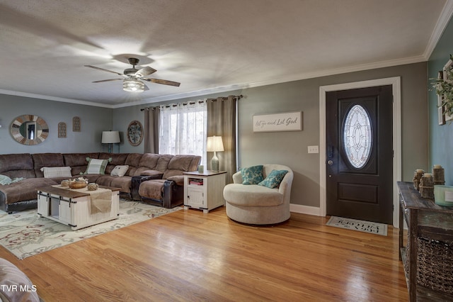 living room featuring ceiling fan, crown molding, a textured ceiling, and light wood-type flooring