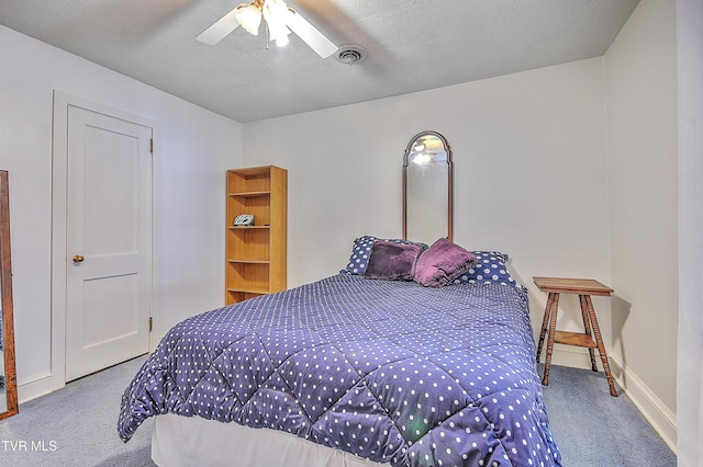 carpeted bedroom with ceiling fan and a textured ceiling