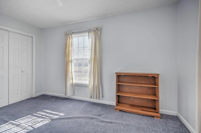 unfurnished bedroom with a textured ceiling, a closet, and dark colored carpet