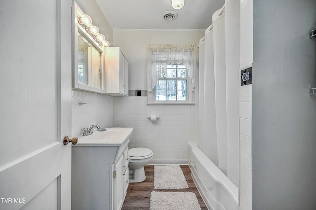 full bathroom with hardwood / wood-style flooring, vanity, shower / bathtub combination with curtain, and toilet