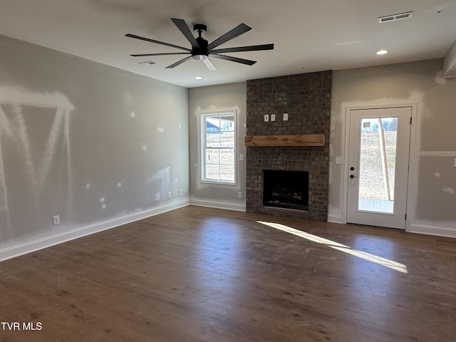 unfurnished living room featuring ceiling fan, dark hardwood / wood-style floors, and a brick fireplace