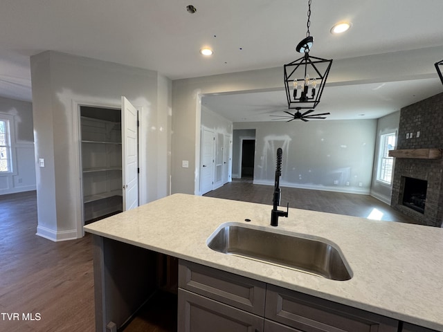 kitchen with a fireplace, sink, ceiling fan, dark hardwood / wood-style floors, and pendant lighting