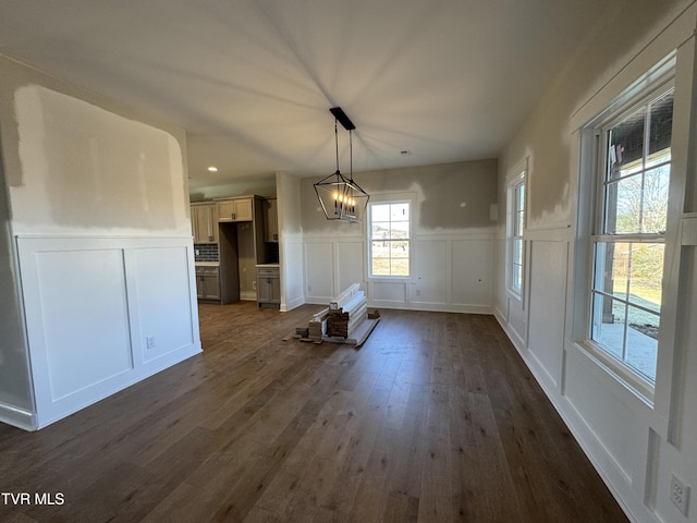 unfurnished dining area with a notable chandelier and dark hardwood / wood-style flooring