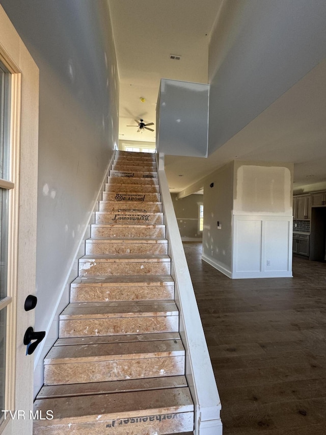 stairs featuring ceiling fan and wood-type flooring