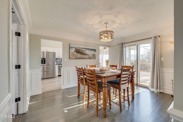 dining area with an inviting chandelier, ornamental molding, hardwood / wood-style floors, and a textured ceiling