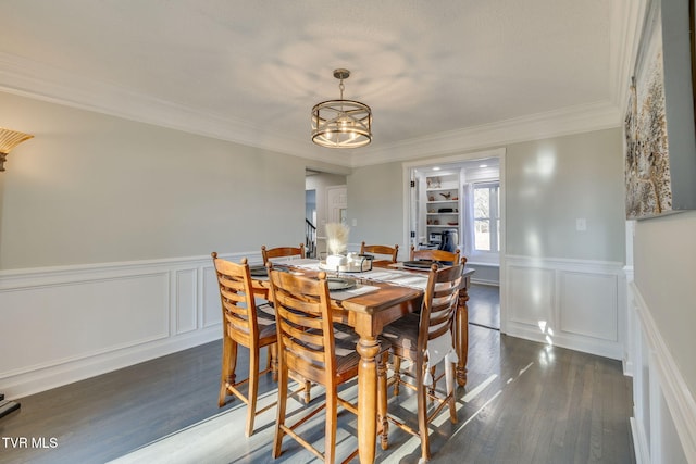 dining area with dark hardwood / wood-style flooring, ornamental molding, and an inviting chandelier