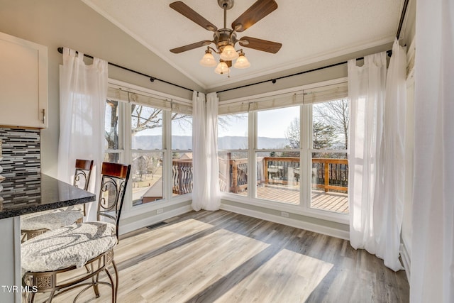 sunroom featuring ceiling fan, a mountain view, and vaulted ceiling