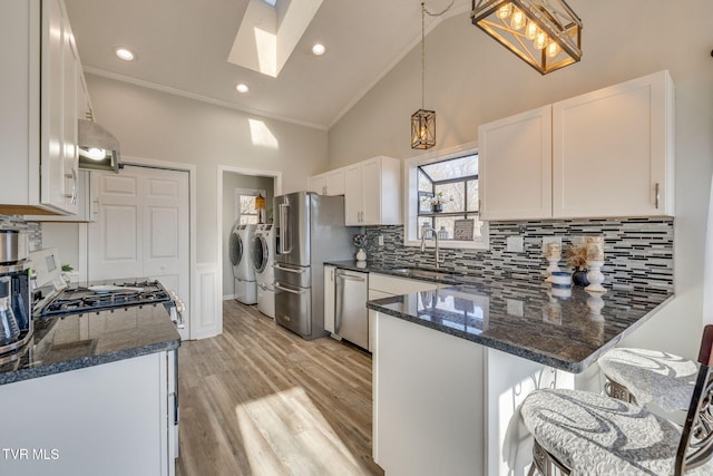 kitchen with white cabinetry, appliances with stainless steel finishes, dark stone countertops, and washing machine and dryer